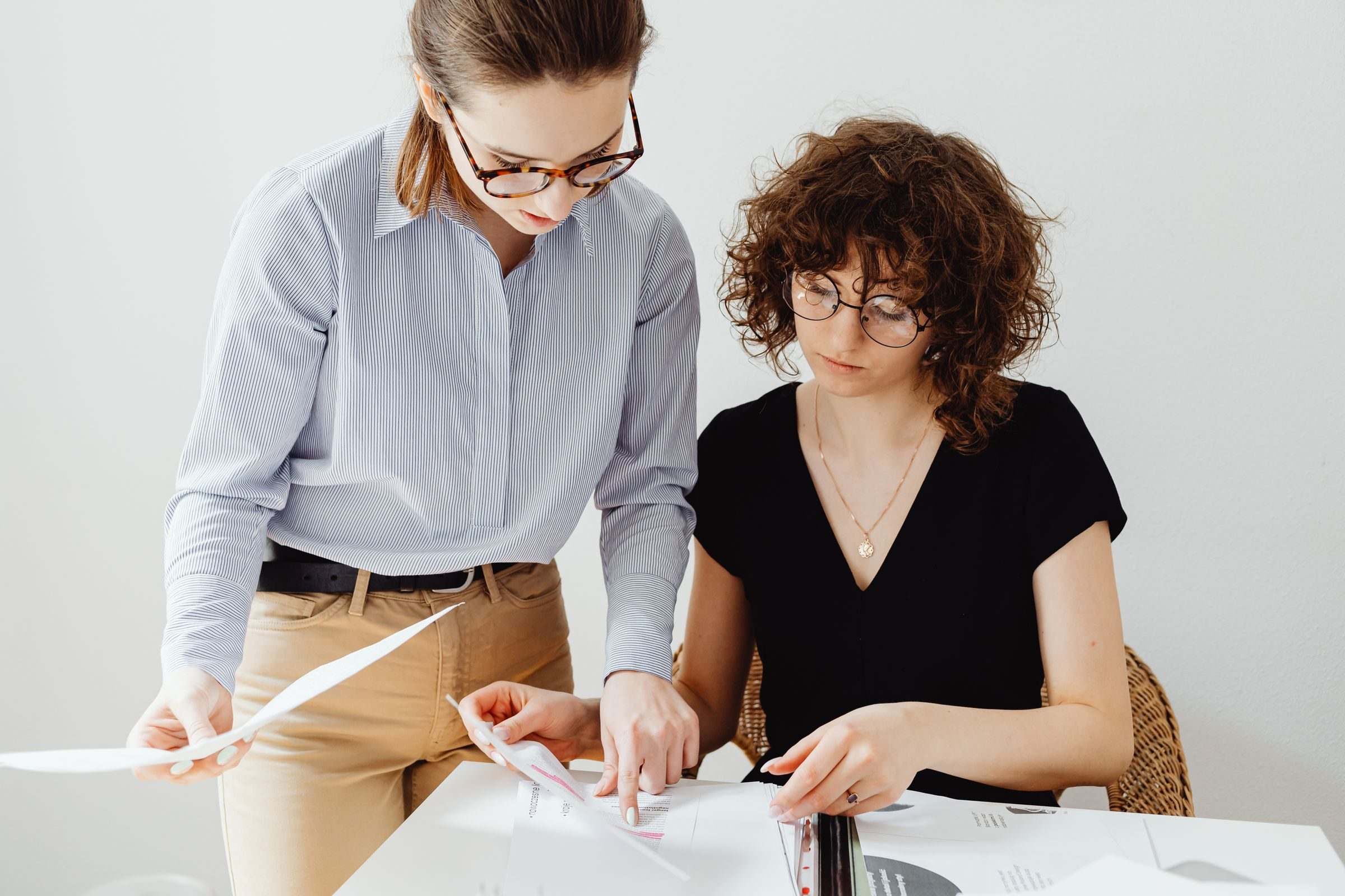 Two accountants side by side reviewing printed figures together