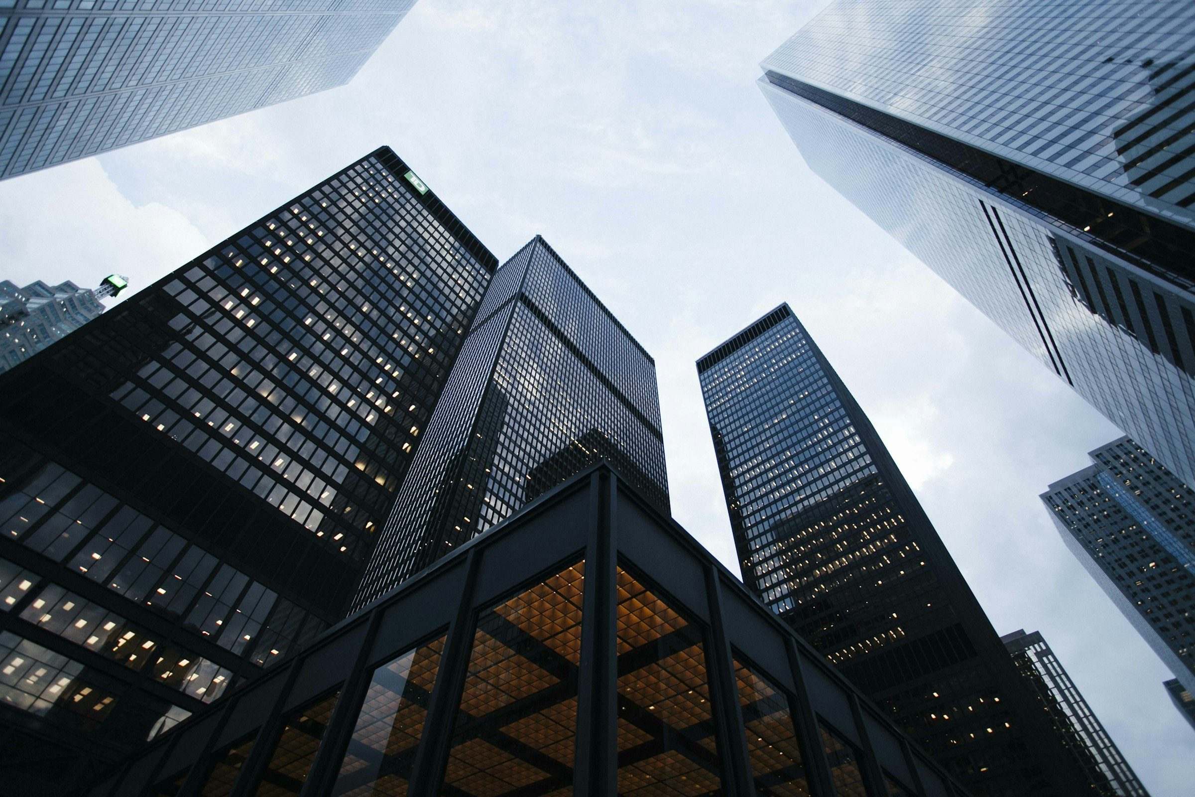 Looking up at glass corporate towers against a pale sky